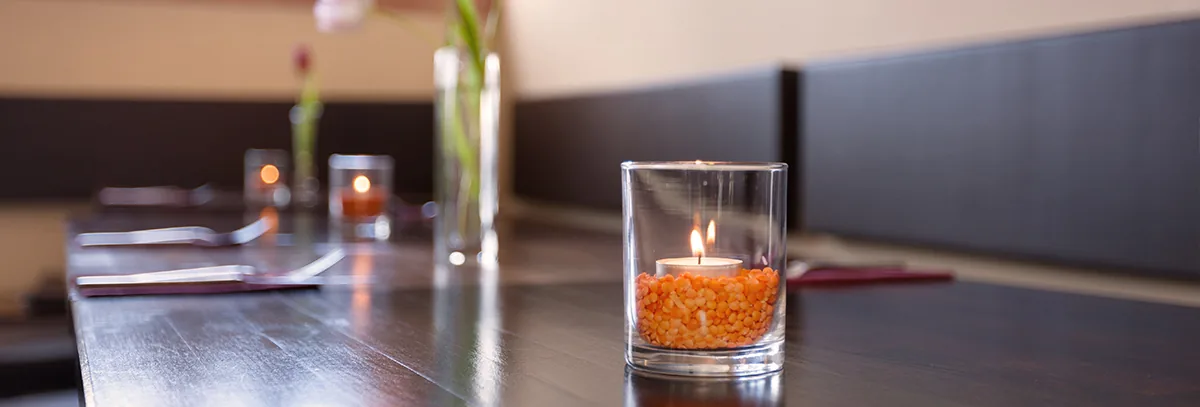 Tischkerze in einem Glas mit orangefarbenen Linsen